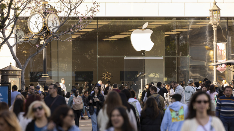 People walk in front of The Americana at Brand Apple store.