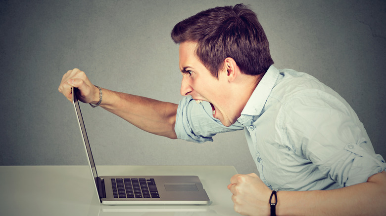 A worker expressing anger at his laptop