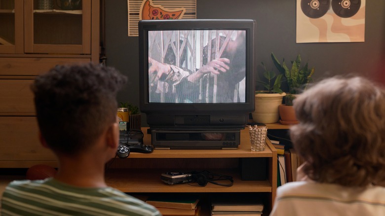 Two children watching a movie on an old CRT TV