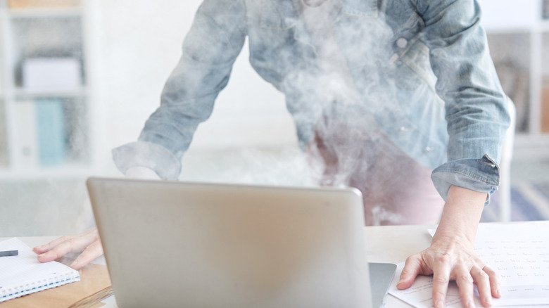 person viewing the smoke coming out of a laptop