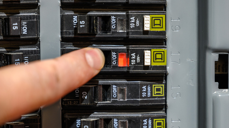 Person resetting a circuit breaker on an electrical panel