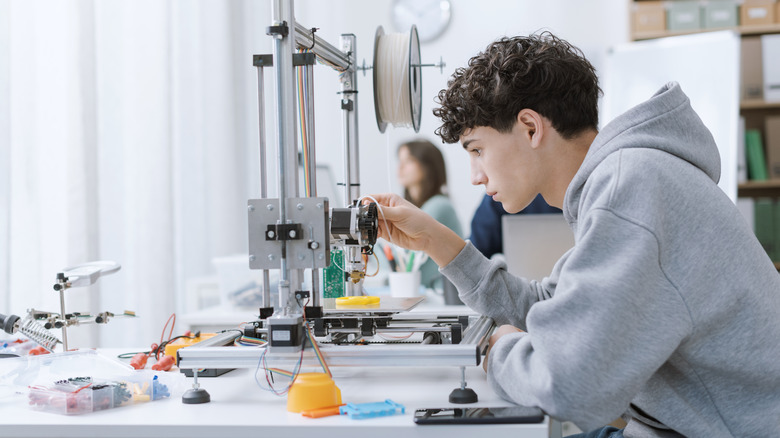 A student adjusting a 3D printer.