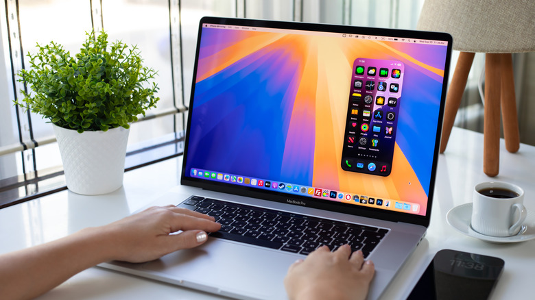 A person using a MacBook in a bright modern office
