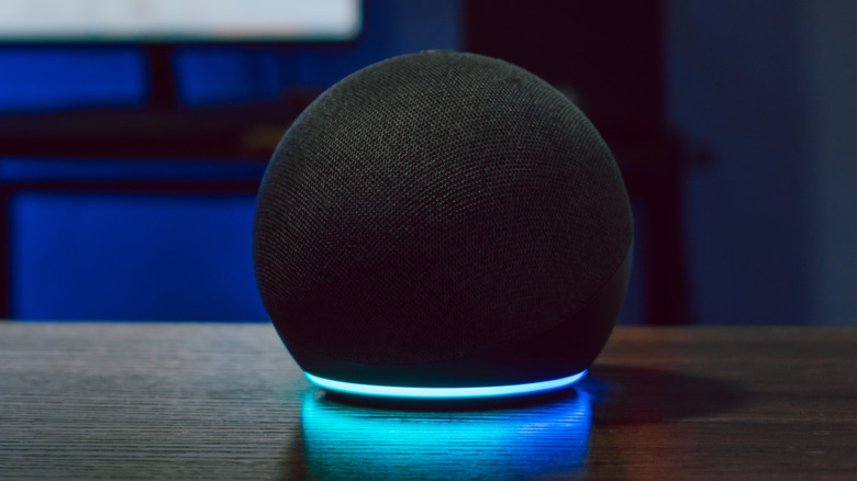 Round smart speaker with blue light ring glowing on a wooden table.