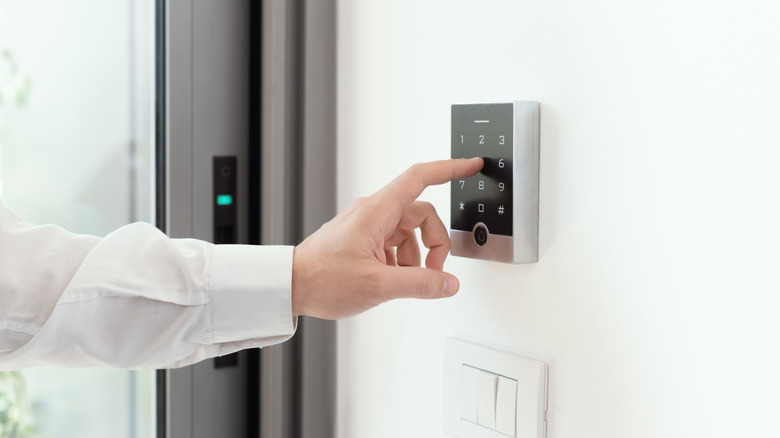 Person entering a code on a wall-mounted smart home security keypad.