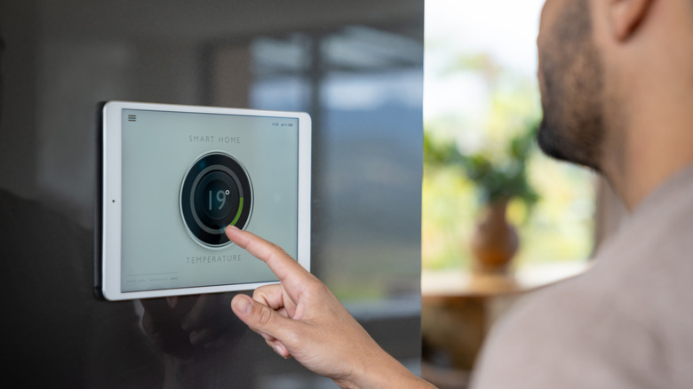 close-up man using smart home screen to change temperature
