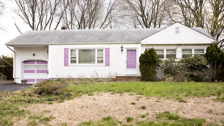An old white home with pink shutters and door