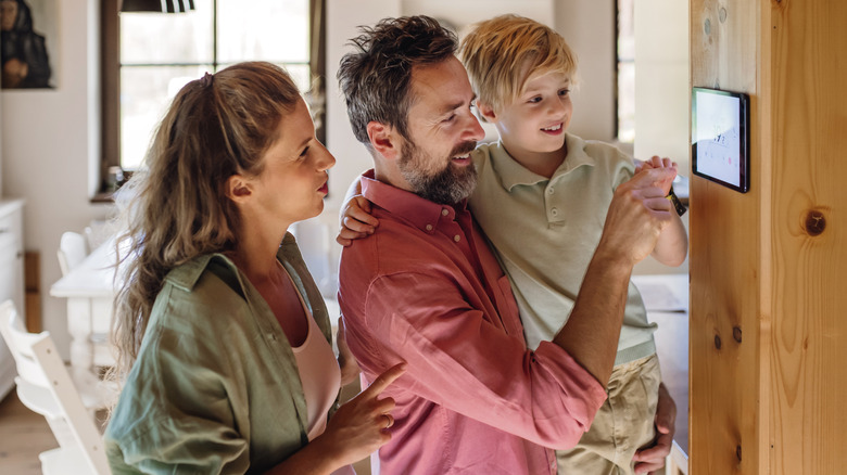 Family with parents and child interacting with a smart home control panel