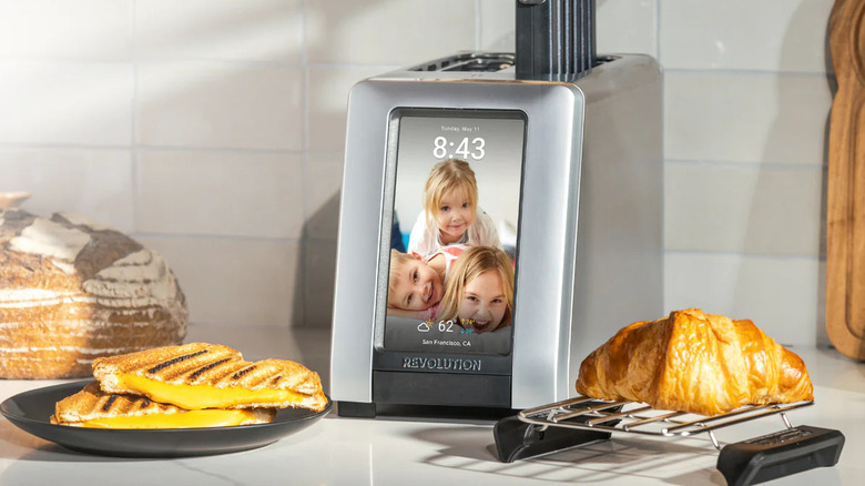 Smart toaster with a touchscreen display on a kitchen counter, toasting bread and a croissan