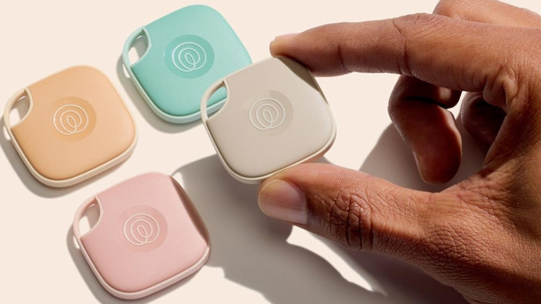 A person picking up a Life360 Tile tracker