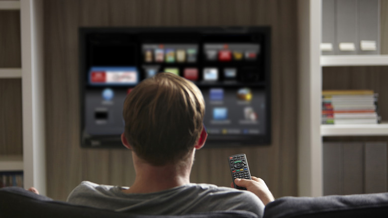 A man holding a TV remote with a smart TV in the background