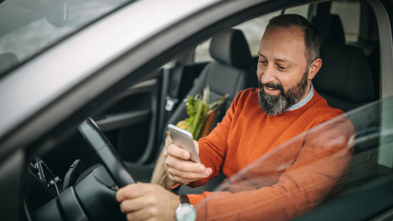 Man holding phone in car