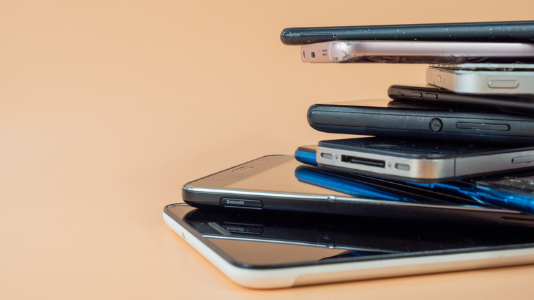 A stack of old electronic devices, including several smartphones.
