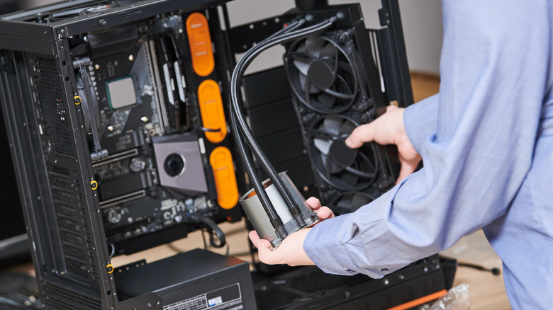 Person installing a liquid cooling radiator inside a desktop PC case.