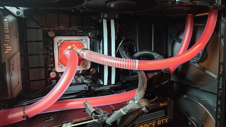 Custom liquid cooling loop inside a gaming PC with red coolant tubes.