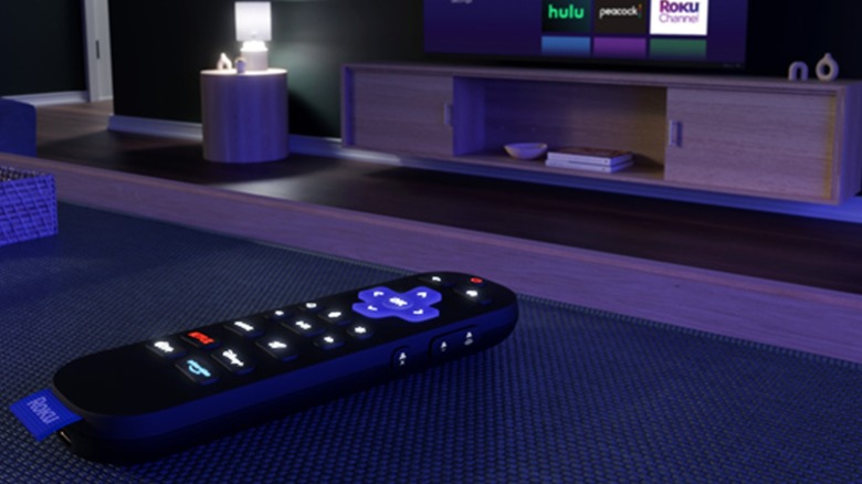 Roku Ultra remote with Roku Ultra and TV in background at night
