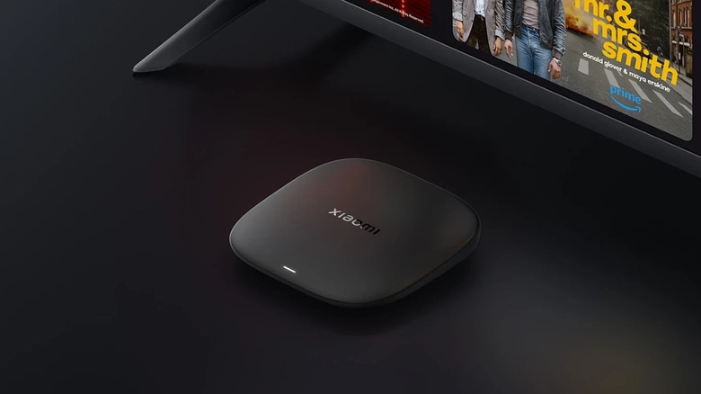 Xiaomi TV Box S streaming device in front of TV on black backgrond