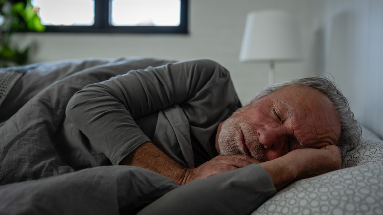 An elderly man sleeping in bed.