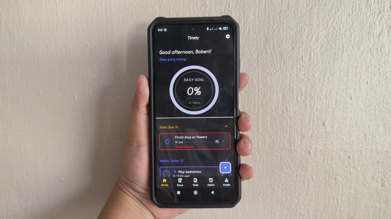 Hand holding Android phone showing Timety app