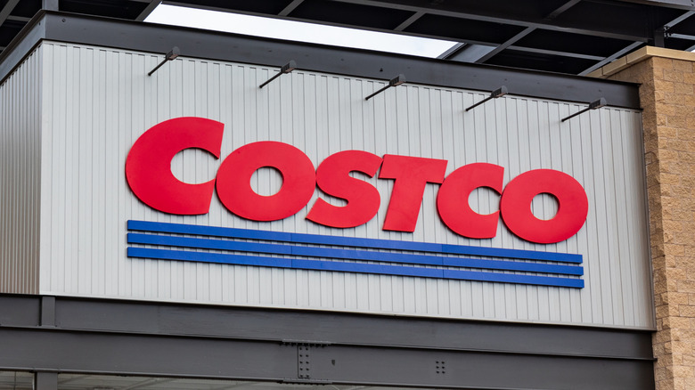 The front exterior of a Costco warehouse, the Costco logo is displayed prominently in the photo