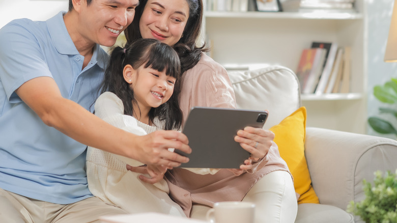 A family of three using a tablet in the living room