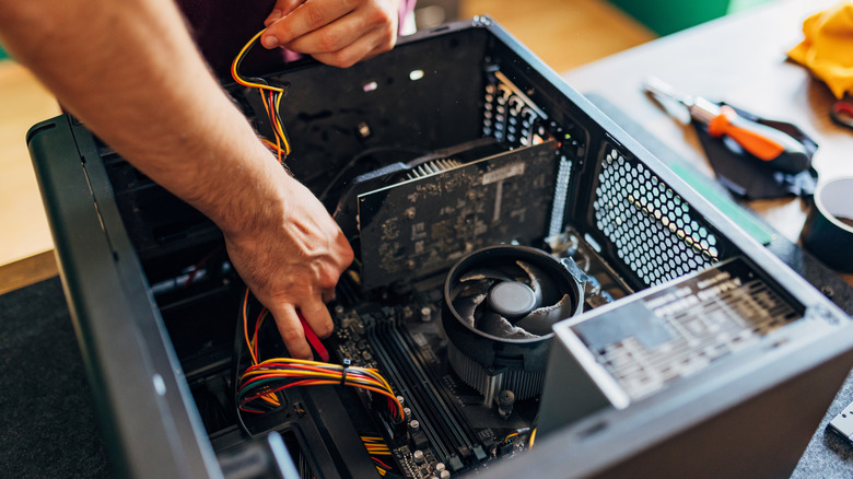 A person working inside a desktop PC case during assembly or repair.