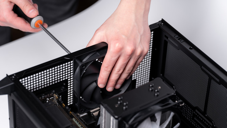 A person installing a cooling fan inside a desktop PC case.