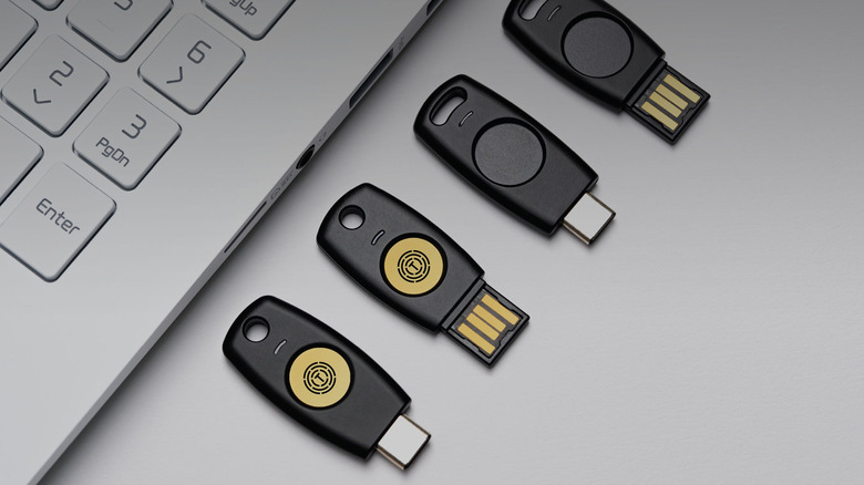 Several USB security key devices on table next to laptop