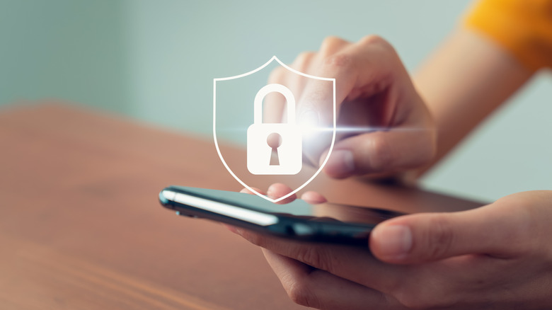 A lock symbol with a person holding a smartphone in the background