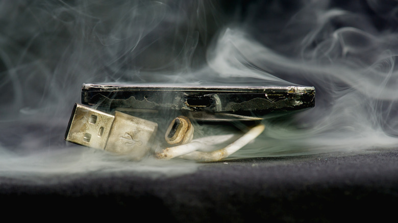 Smoldering smartphone with burnt cable
