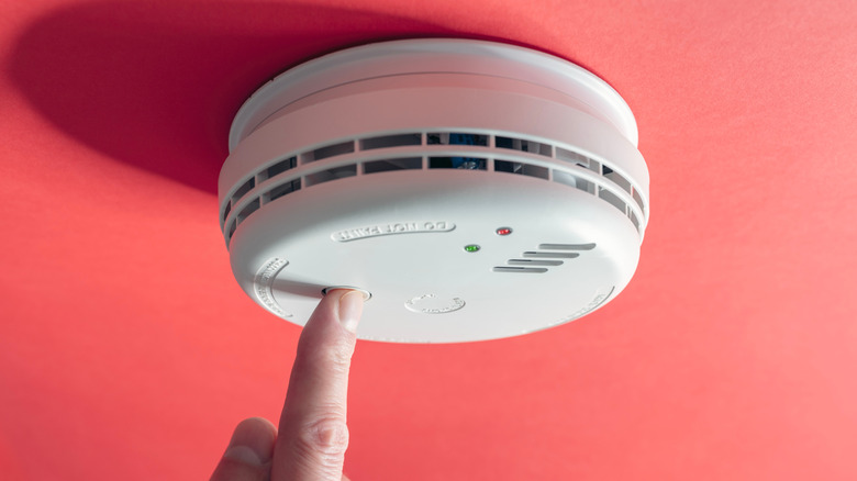 Person pushing button on smoke detector