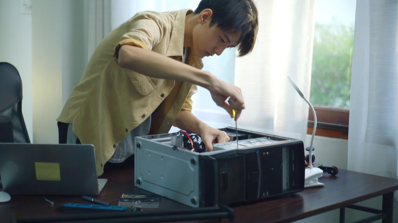 Person using a screwdriver while working inside an open desktop PC case.