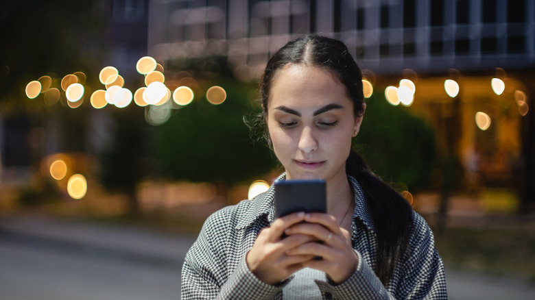 Woman focused intently on a smartphone as she texts someone