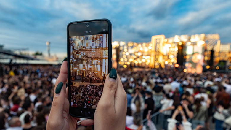 person recording a concert on a smartphone