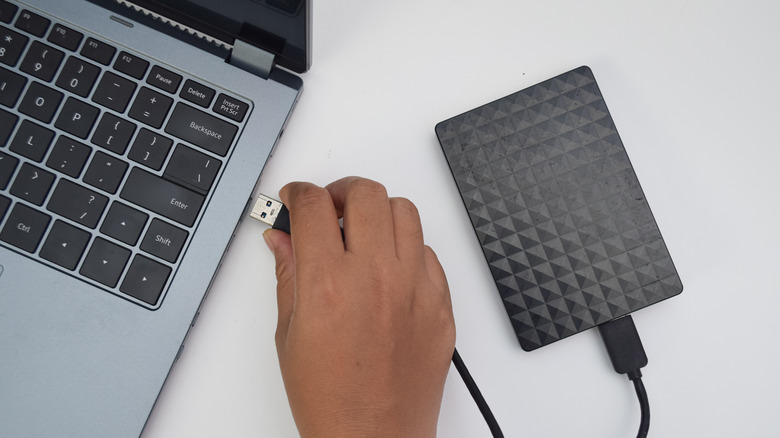 A person connecting an external drive to a laptop
