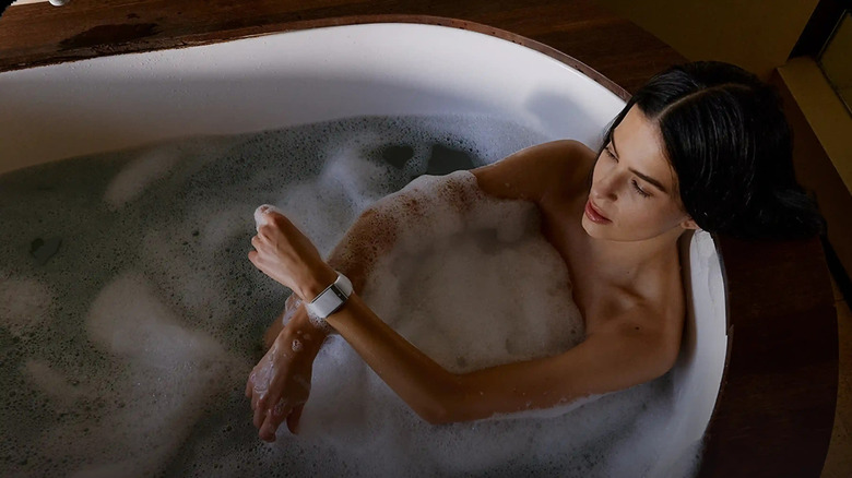 A woman in a bath tub wearing a Whoop band
