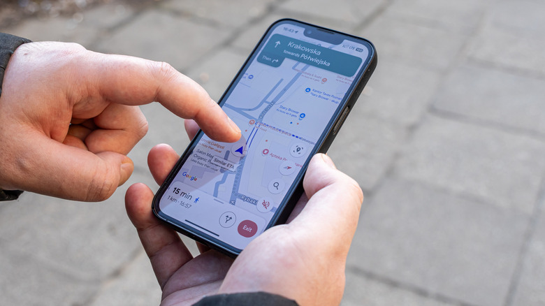 person using smartphone navigation app with google maps directions on screen