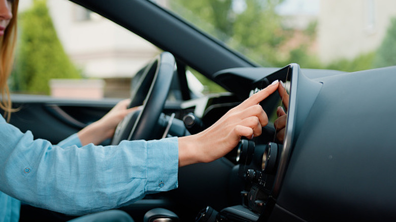 Driver touching a car's touchscreen while holding the steering wheel