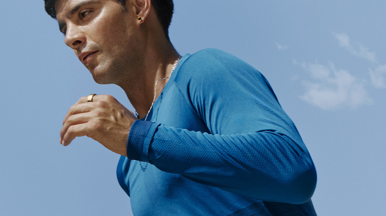 A man running outside in a blue shirt while wearing an Oura Ring 4.