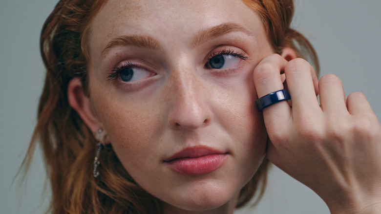 Close-up of a young woman with red hair wearing an Oura Ring 4.