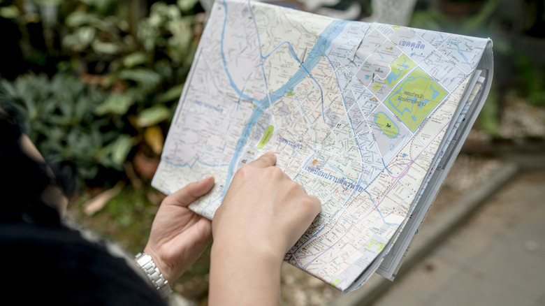 A woman using a paper map to find her way around a city.