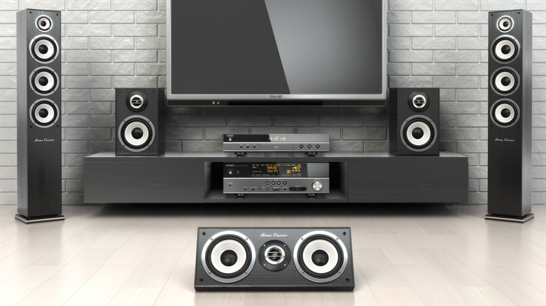 A large silver sound system is by a television, the sound system and the image in general looks incredibly modern