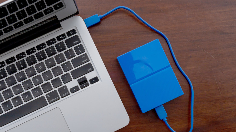 An external hard disk connected to a laptop, symbolizing syncing, backup, or file movement.