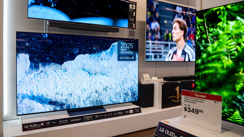 LG OLED TV displayed in an electronics store with a price sign and other TVs in the background.