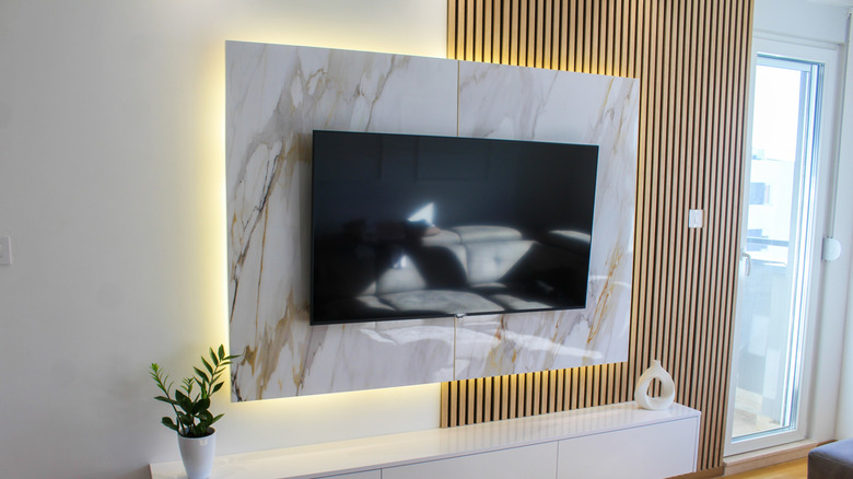 Flat-screen TV mounted on a decorative marble and wood accent wall in a modern living room.