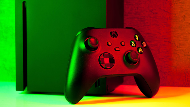 Xbox Series X console with controller under red and green lighting.