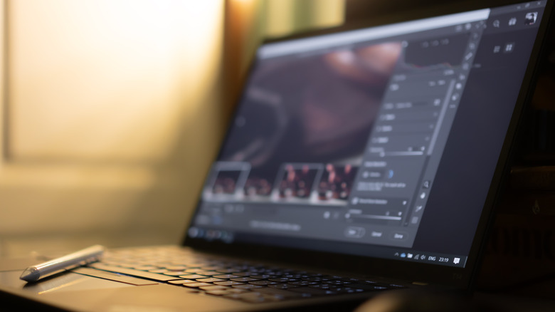 Laptop with a stylus placed on the touchpad running a video and video editing software