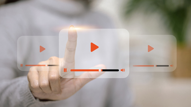 A finger scrolling through virtual video screens