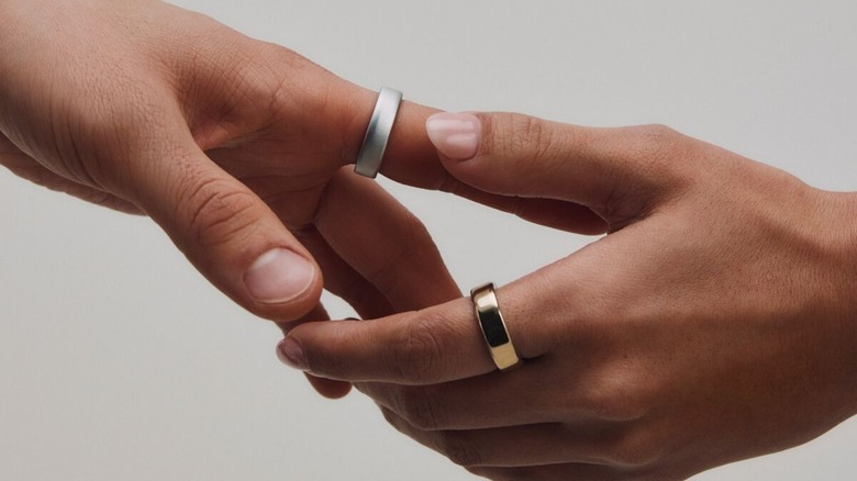 Two Oura rings on hands that are shaking