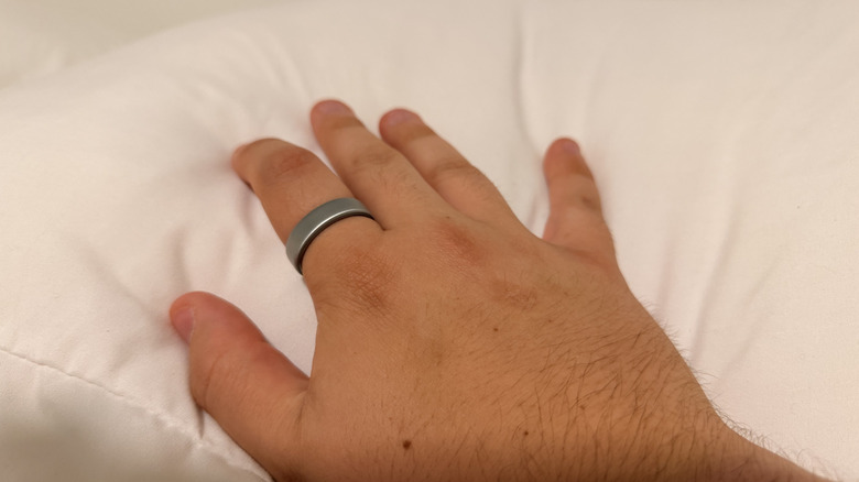 Oura Ring 5 on my finger on top of a white pillow